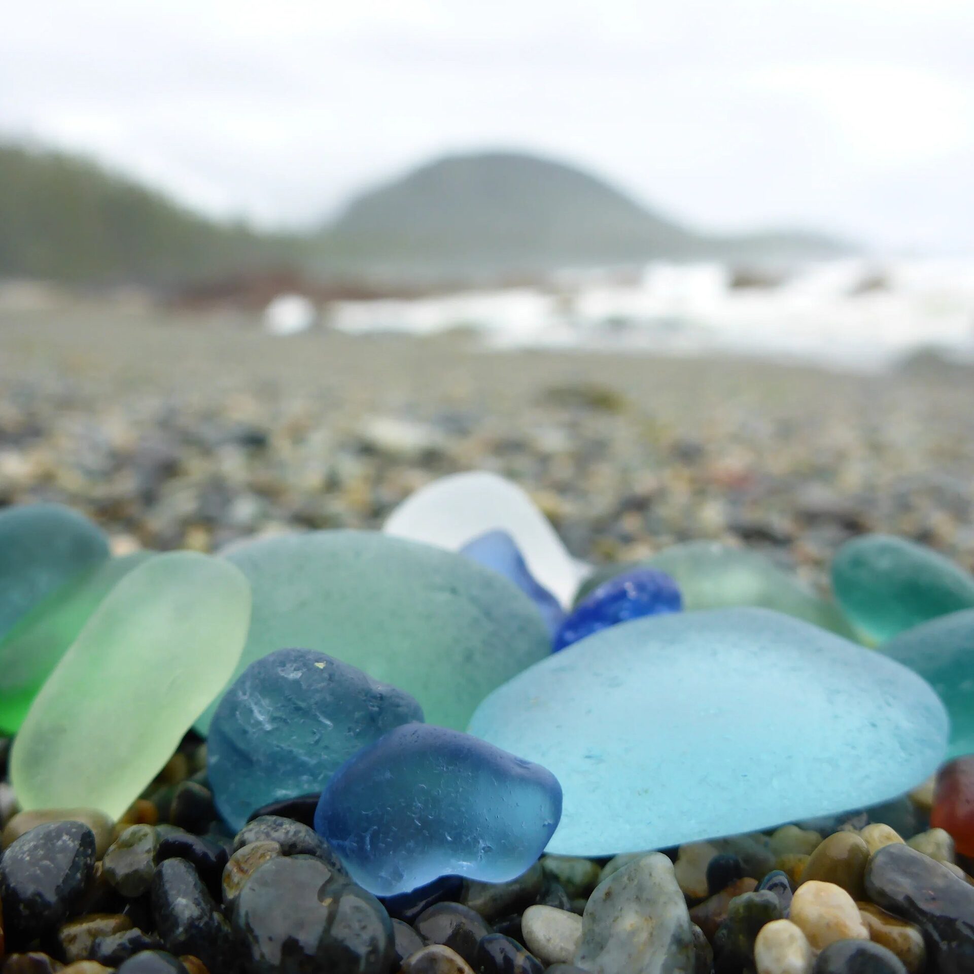 blue and green seaglass nested on a gravel beach
